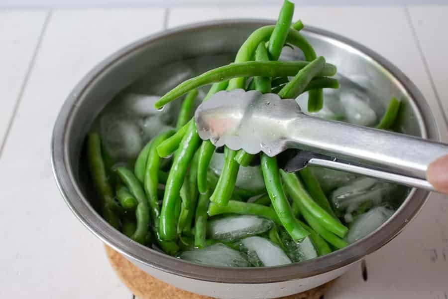 Green beans being placed in a pot of ice water.