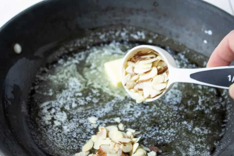 Almonds in a pan along with melted butter.