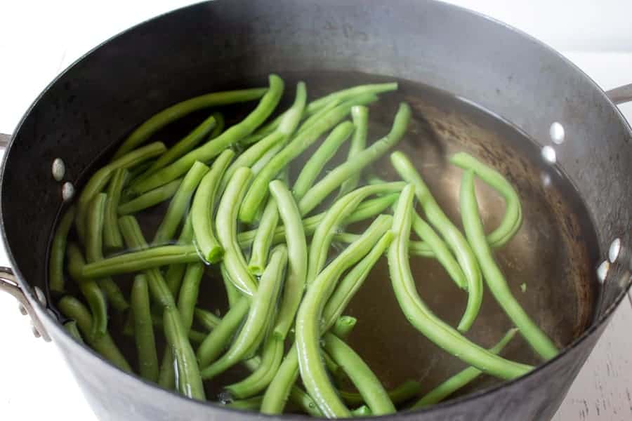 A pot filled with water and green beans.