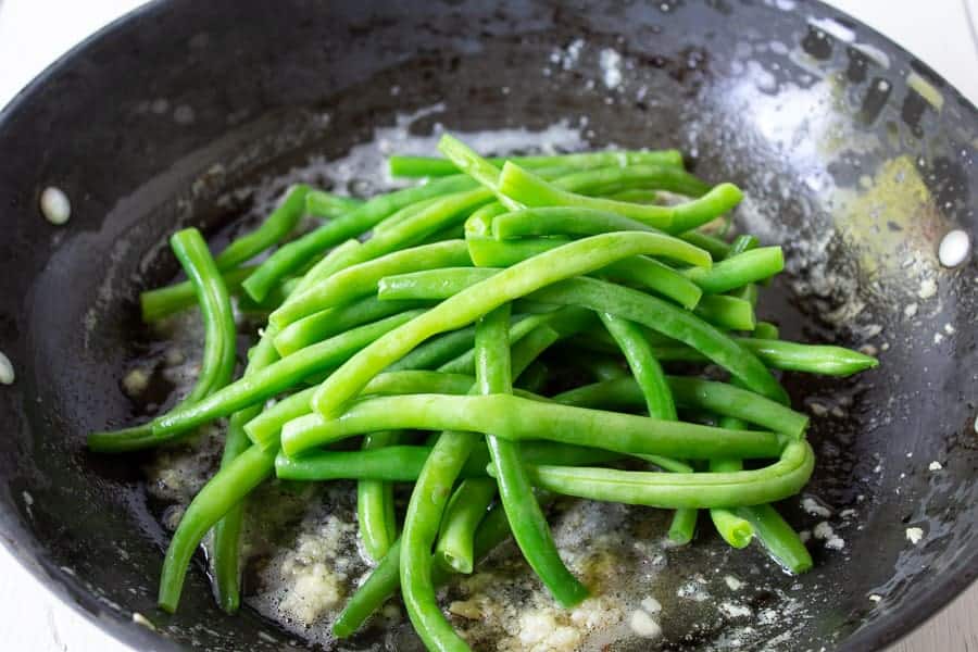 Green beans in a saute pan with butter and garlic. 