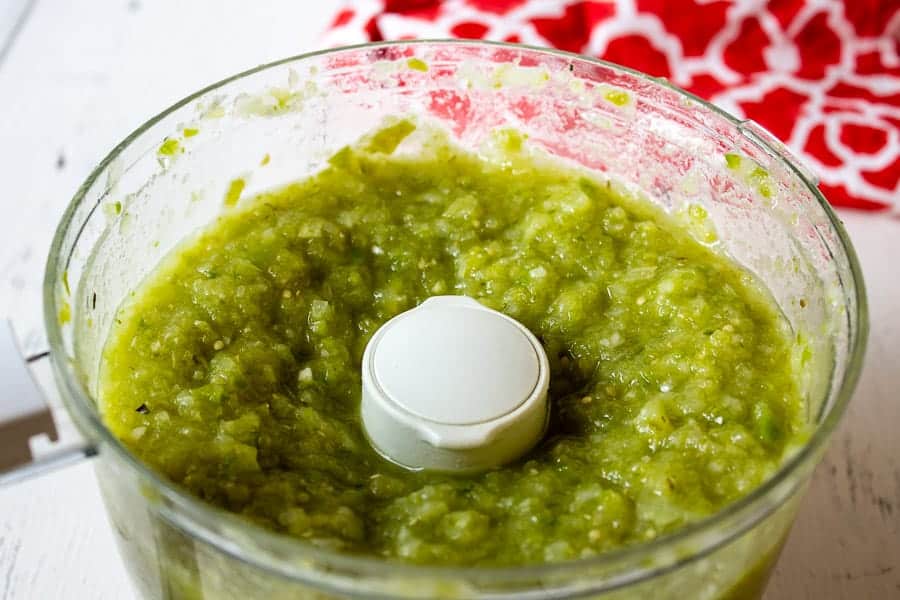 Chopped tomatillos, peppers and onions in a food processor.