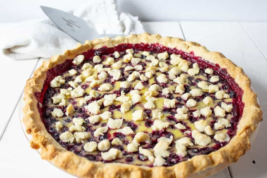 A whole huckleberry pie on a white board.