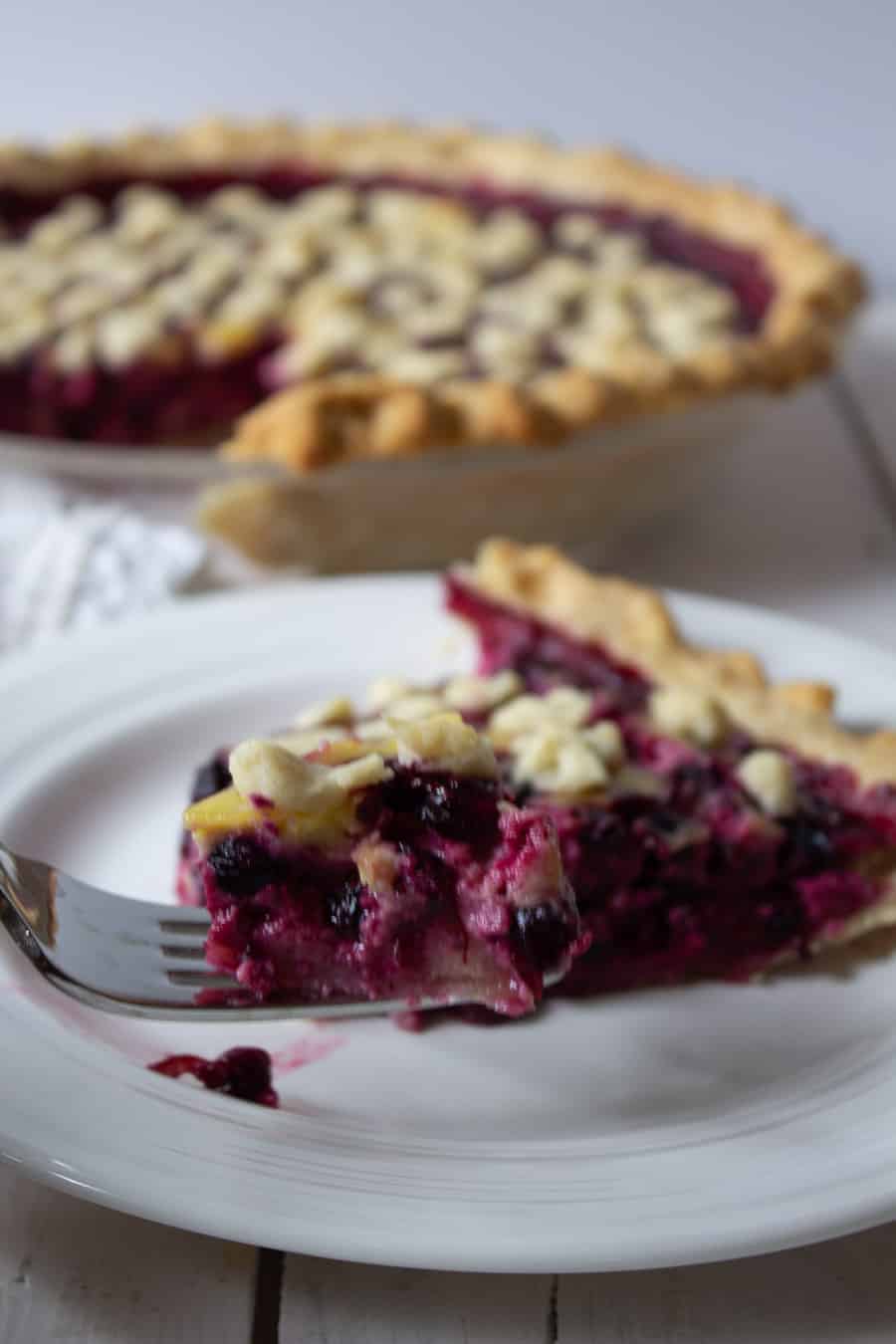 A slice of pie with a fork taking a piece off the top of the slice.