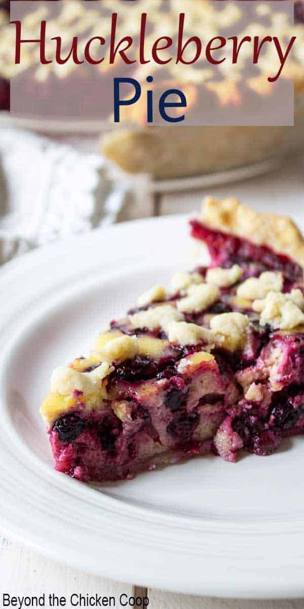 A slice of berry pie on a white plate with a whole pie behind the slice.