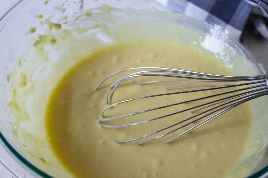 A wire whisk mixing a custard mixture.