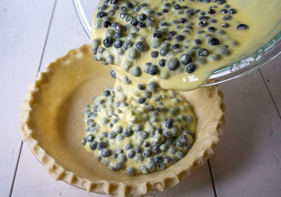 Pouring a pie mixture into a pie shell.