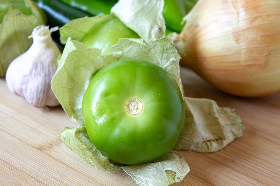 Fresh tomatillo with paper husk pulled back from the fruit.