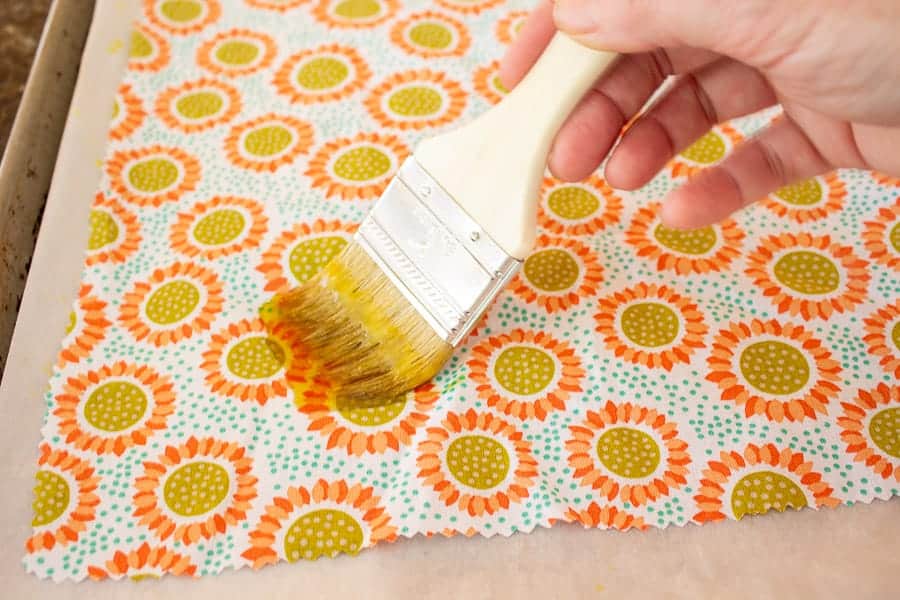 A disposable paintbrush brushing melted wax onto fabric.