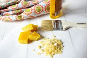 Beeswax, pine resin and a paint brush on a white surface.