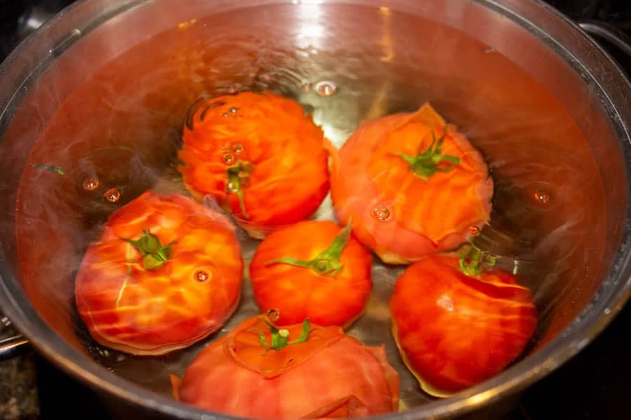 Fresh tomatoes in a pot of boiling water.