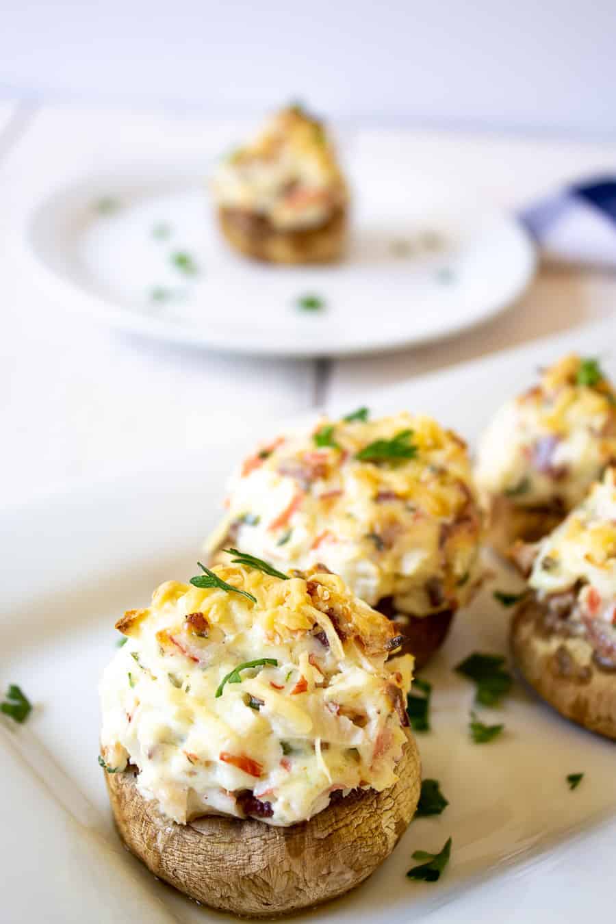 Stuffed mushrooms topped with chopped parsley on a white platter. 