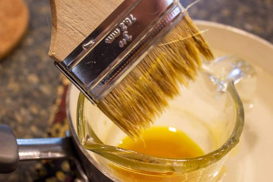 A disposable paint brush dipping into a wax mixture.