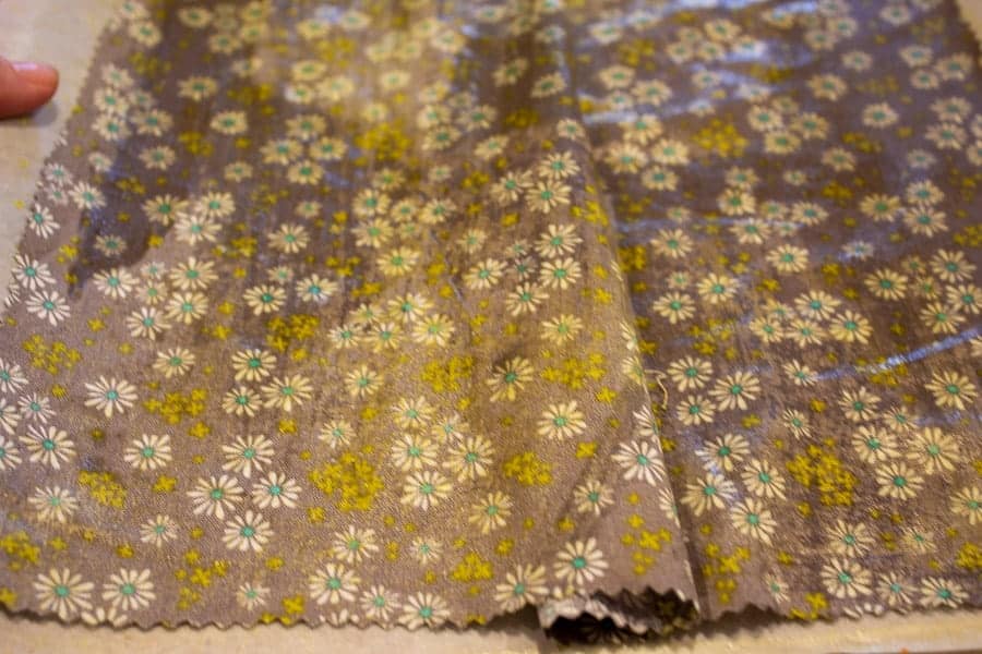 Floral fabric covered with beeswax on a baking sheet.