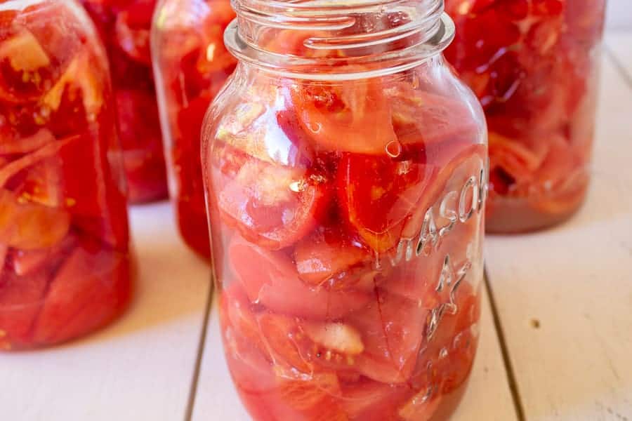 Chopped tomatoes in a quart sized canning jar.