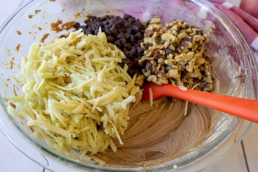 Apples, walnuts and chocolate chips in a bowl of cake batter.