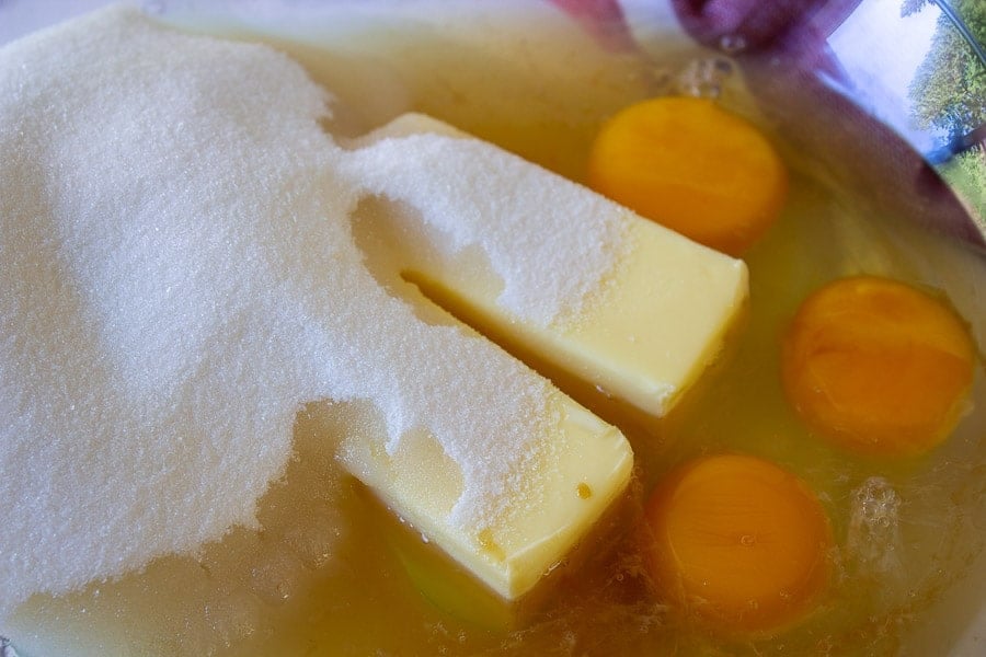 A bowl filled with butter, sugar, eggs, and vanilla.