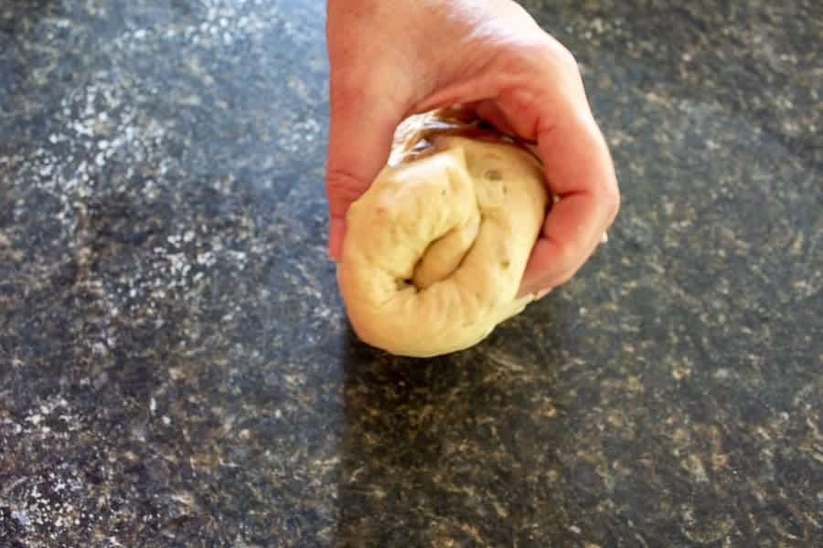 A log of bread dough held with one hand.
