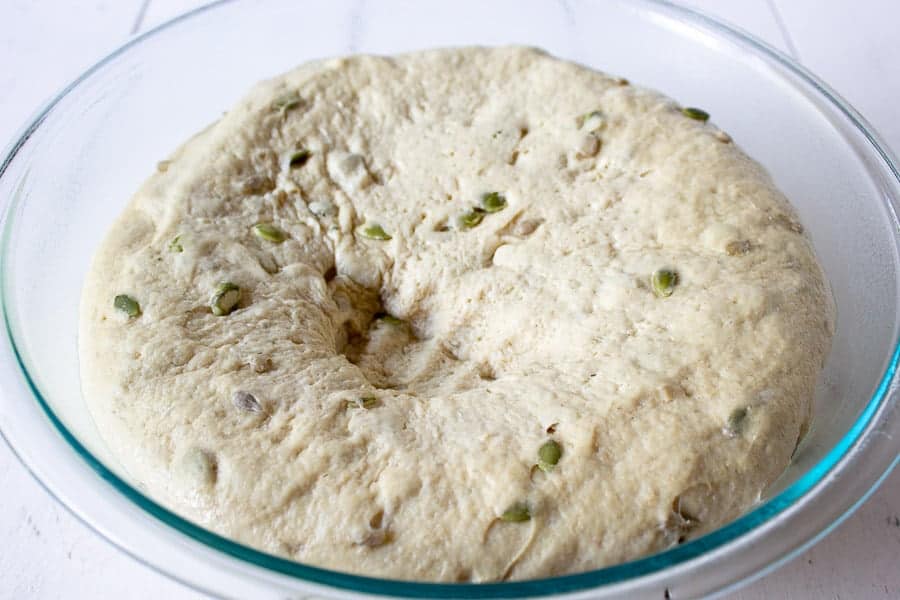 Bread dough with seeds in a glass bowl.