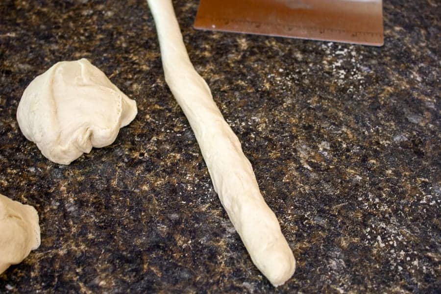 A long rope of pretzel dough on a counter.