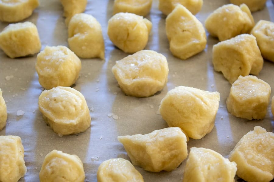 Pretzel dough on a baking sheet with sprinkled salt.