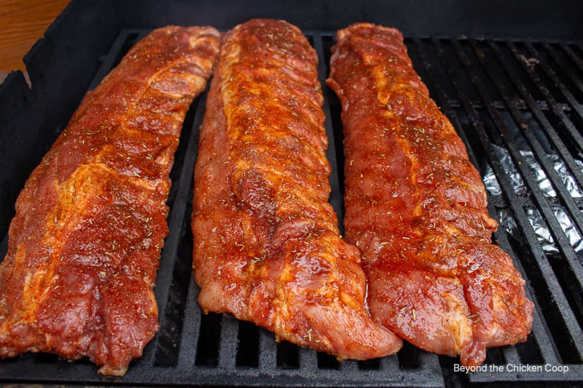 Ribs covered with a dry rub on a grill.