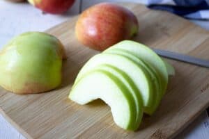 Slices of a green apple on a cutting board.