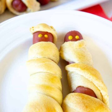 Hot dog mummies on a white plate.