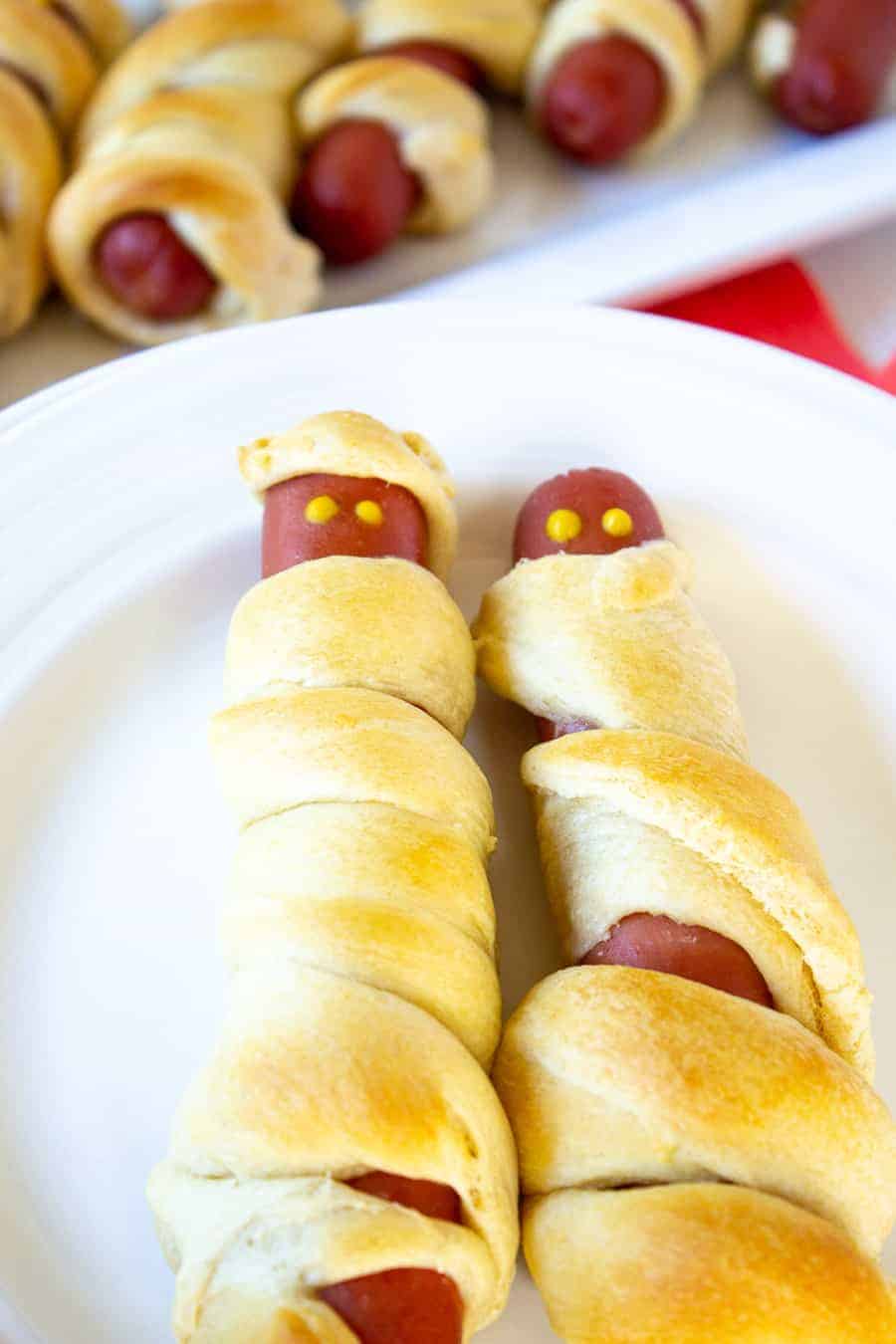 Hot dog mummies on a white plate.