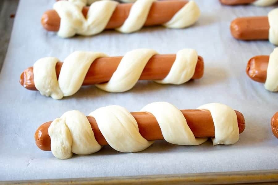 Hot dogs on a baking sheet lined with parchment paper.