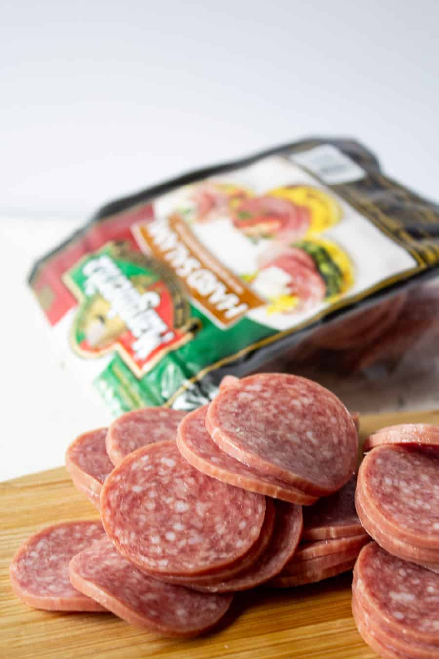 Slices of hard salami stacked on a cutting board. 