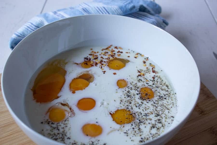 Milk, eggs and seasonings in a large white bowl. 
