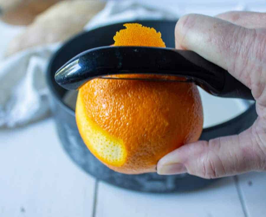 Peeling an orange zest with a peeler.