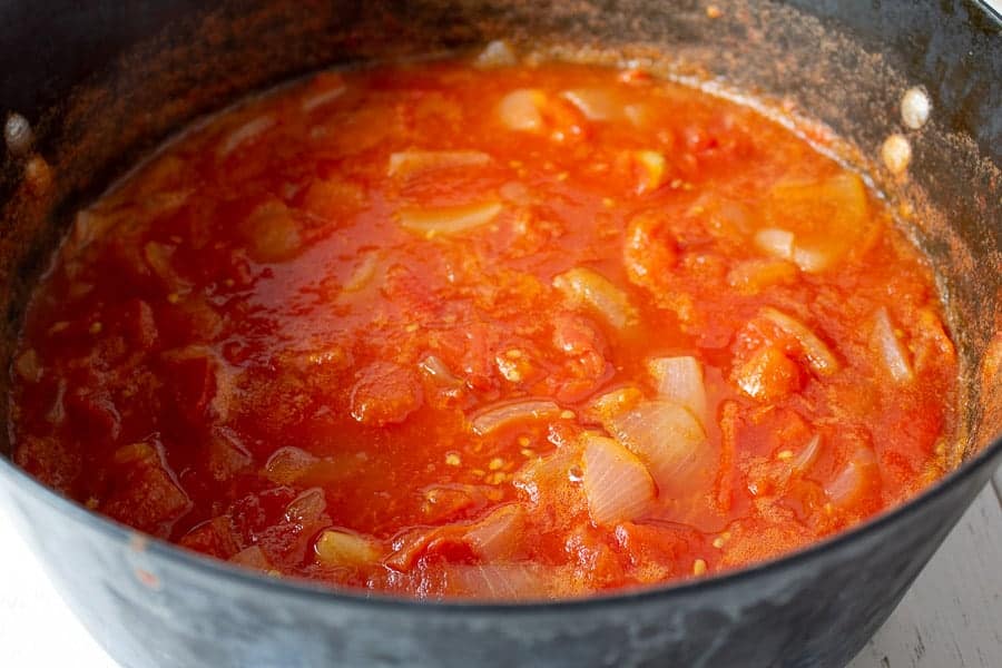 Cooked tomatoes in a large black pot. 