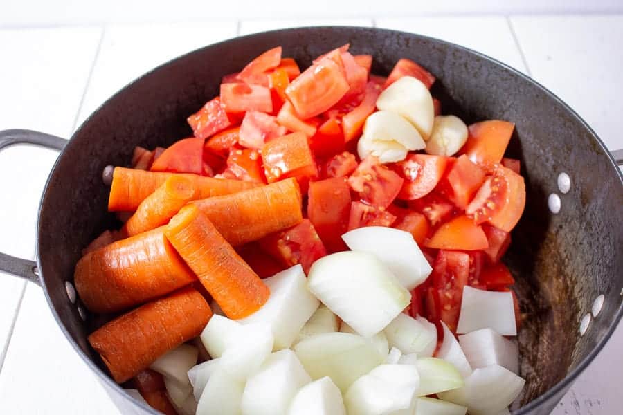 Fresh chopped tomatoes onions, carrots and garlic in a large pot.