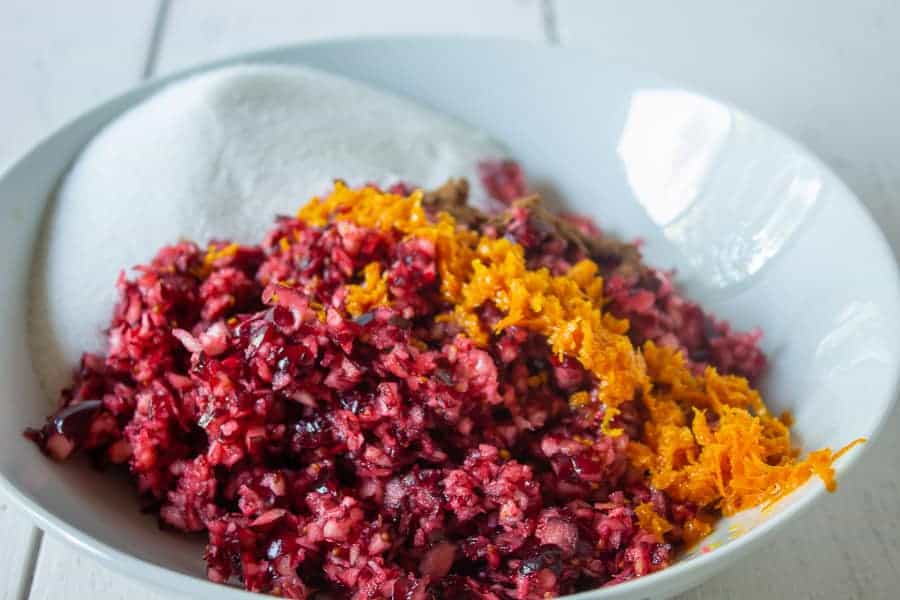 A bowl filled with fresh chopped cranberries, orange zest and cinnamon. 