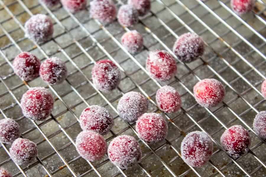 A baking rack with sugar coated cranberries on top of rack.