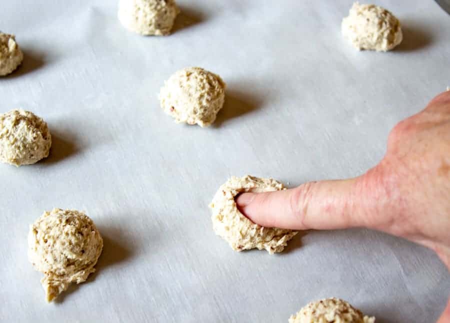 Pushing down on a round mound of cookie dough.