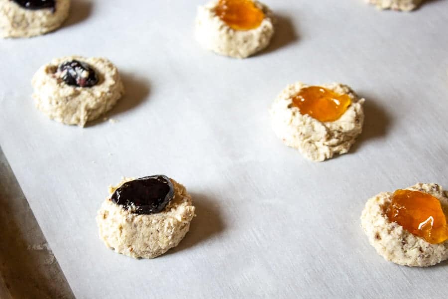 Thumbprint Cookies filled with jam on a baking sheet.