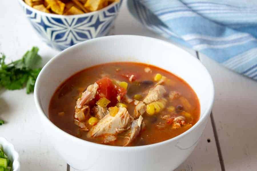 A bowlful of turkey soup with tomatoes and veggies. 