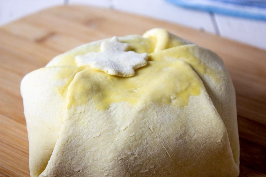 Decorative puff pastry being added to a round of brie.