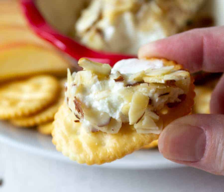 A cracker topped with cheese, almonds and honey.
