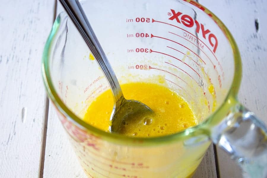 Egg yolks and sugar combined together in a large glass measuring cup.