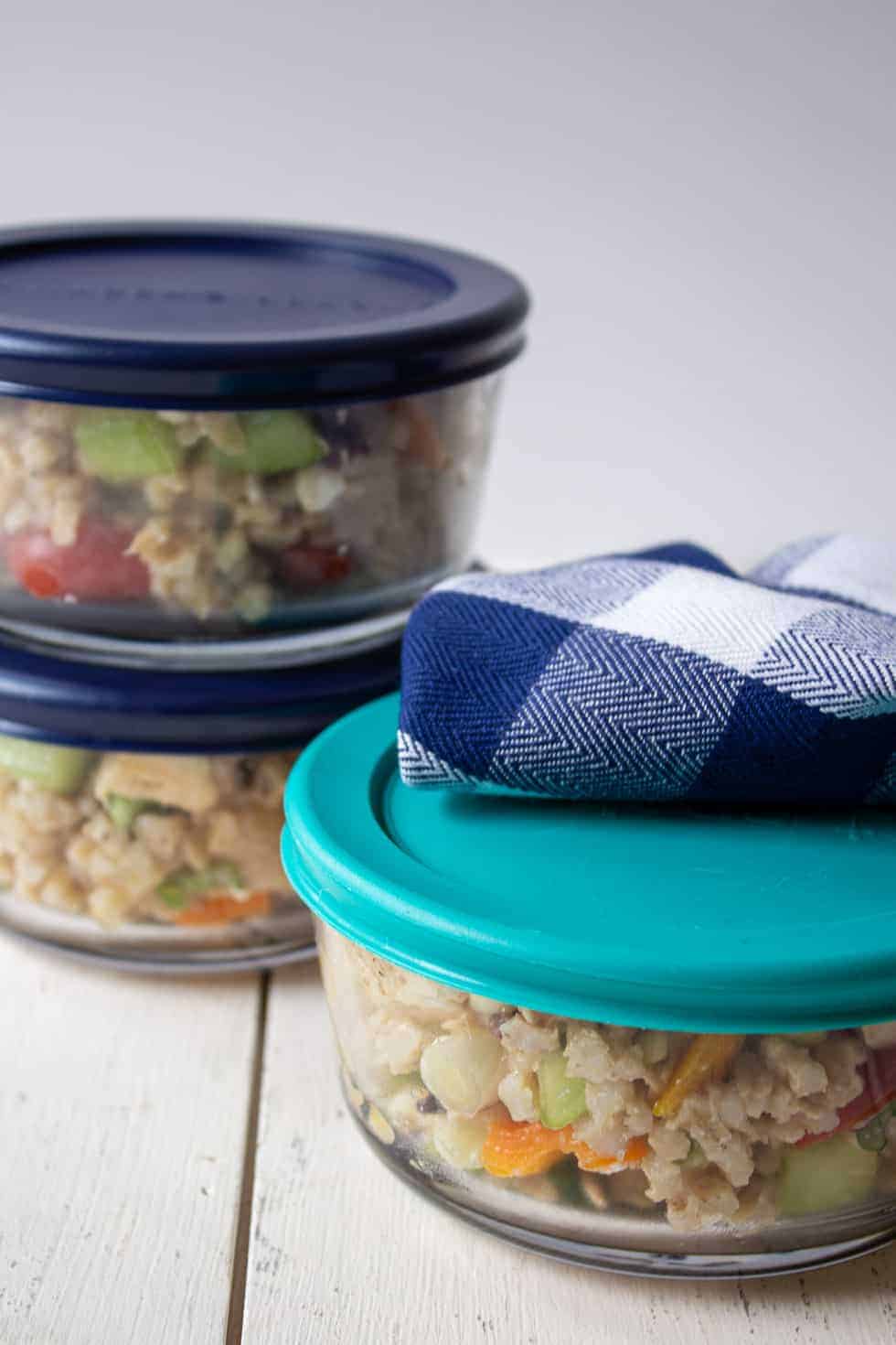 Glass containers filled with barley salad and topped with colorful lids. 