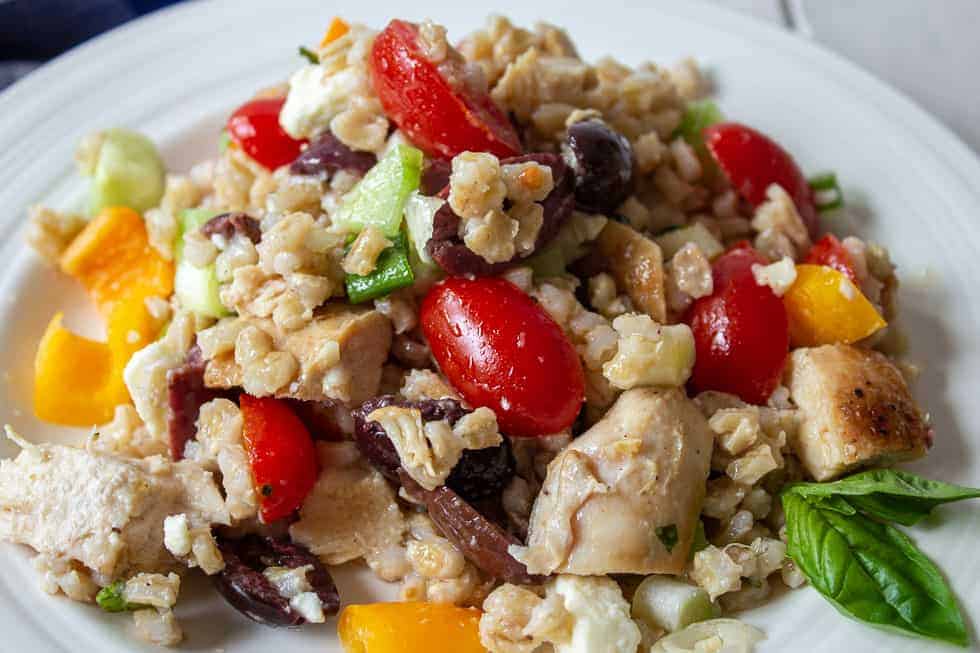 Barley with fresh veggies and basil on a white plate.