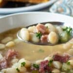 A spoonful of soup with beans and ham.