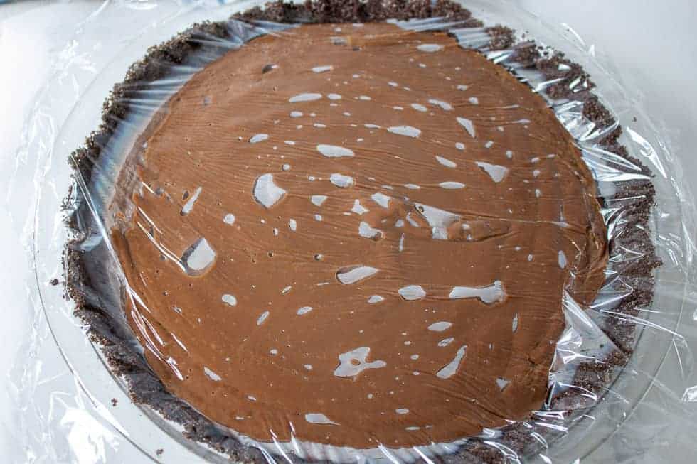 Plastic wrap on top of a chocolate pie.