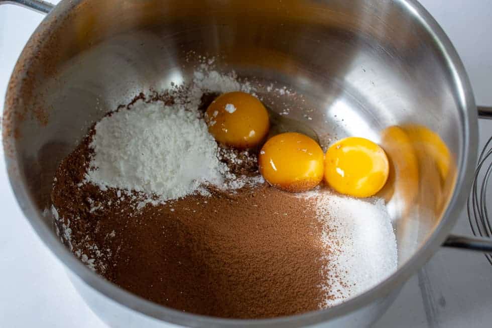 A pot with egg yolks, sugar and cocoa powder.