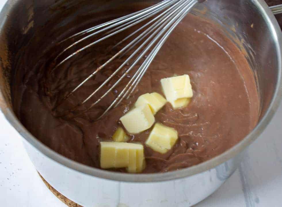 Butter cubes added to a rich chocolate mixture in a pot.