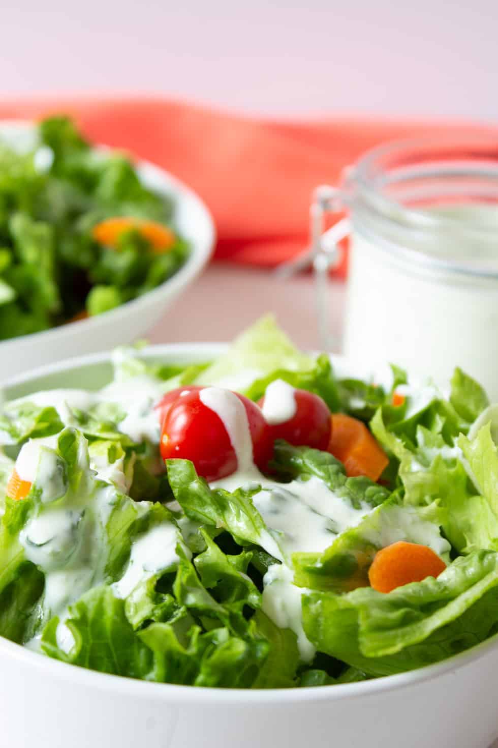 A green salad topped with a creamy white dressing. 