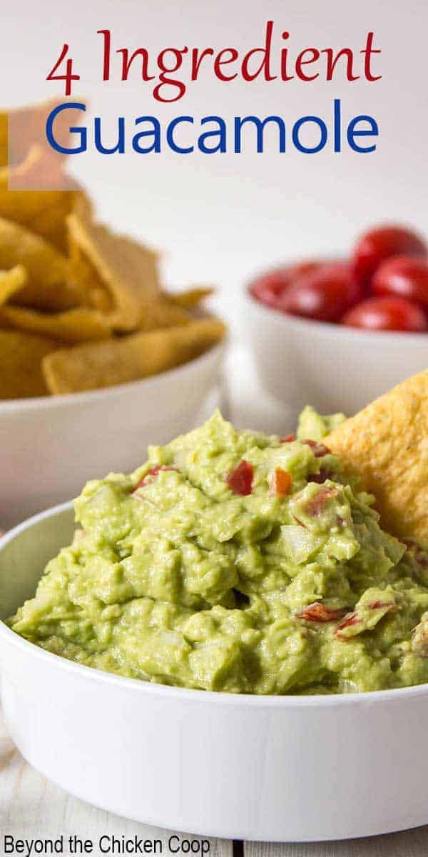 A bowl filled with guacamole with a chip sticking in one end. 